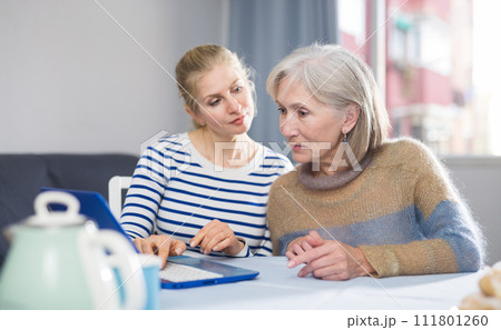 Mature woman and her daughter are viewing the information on a laptop 111801260