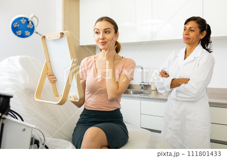 Positive young woman evaluating quality of cosmetological procedures 111801433
