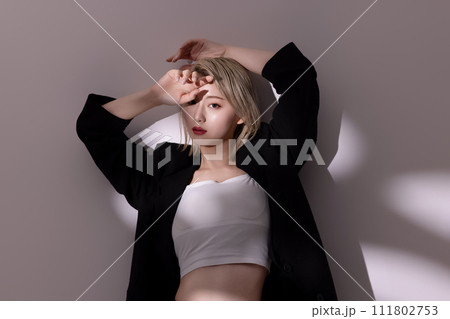 黒いジャケットを着た若い女性の光と影背景のポートレート 111802753