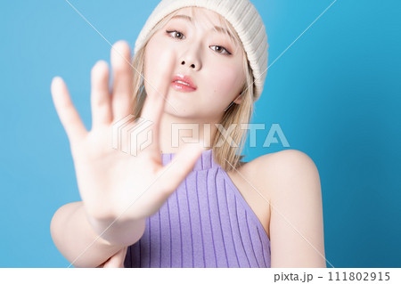 青背景で撮影をした若い女性のポップなメイクアップイメージ 111802915