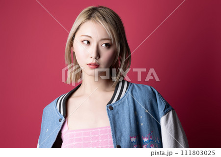 ピンク背景で撮影をした若い女性のカジュアルなポートレート 111803025