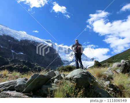ニュージーランド、ロブロイ氷河のある山頂を眺める登山者の男性の後ろ姿 111806549