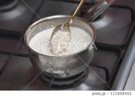 Boil milk in a small saucepan on the stove. Prepare milk porridge. Boil milk in a small saucepan on the stove. Prepare milk porridge. 111808402