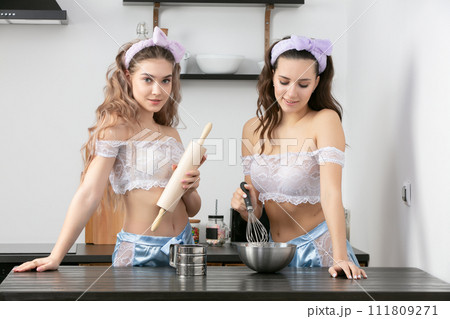 Two beautiful girls in the kitchen. Girlfriends cook food at home in the morning. Two beautiful girls in the kitchen. Girlfriends cook food at home in the morning. 111809271