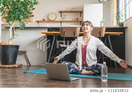 家でノートパソコンで動画を見ながらオンラインヨガ・オンラインレッスンをするアジア人女性 111810612