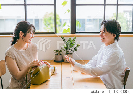 カフェ・レストラン・外食で会計時に支払いをしようとする女性と断る男性 111810802