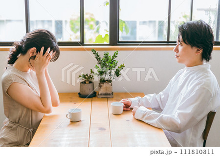 カフェ・家のダイニングで別れ話・深刻な話をする男性とショックを受ける女性 111810811