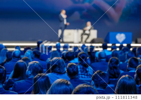 Business conference presentation with speaker on stage and audience listening Business conference presentation with speaker on stage and audience listening 111811348