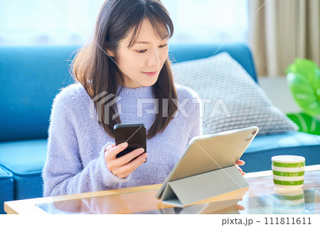 スマートフォンとタブレットPCの画面を見比べる女性 111811611