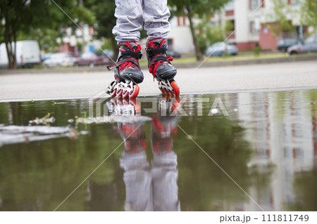 Roller skating. Legs in roller skates ride through a puddle. Roller skating. Legs in roller skates ride through a puddle. 111811749