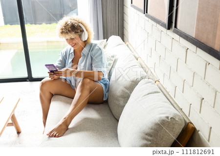 Relaxed Woman with Headphones Using Smartphone on Couch 111812691