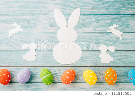 Easter Day Concept. Top view holiday banner background web design white colorful easter eggs and paper bunny rabbit on blue wood background with copy space, celebration greeting, overhead, template 111815500