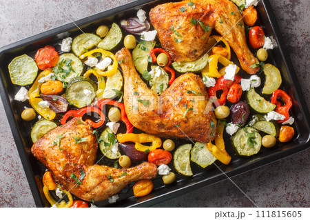 Homemade baked chicken quarters with vegetables and feta cheese close-up on a baking sheet. Horizontal top view 111815605