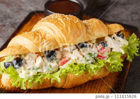 Chicken salad on a flaky butter croissant on a wooden board. Horizontal 111815626