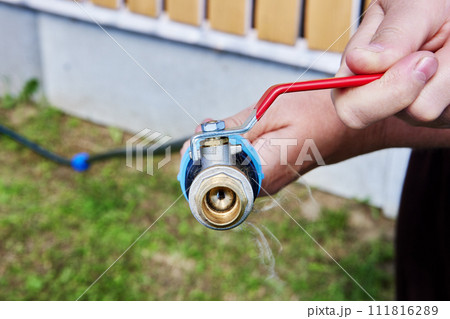 Metal ball valve with lever is attached to end of HDPE pipe using an adapter with compression clamp, system is used for watering garden. 111816289