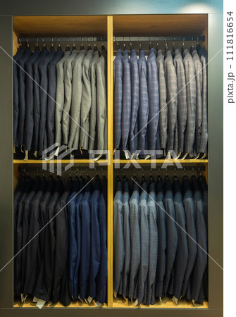 A row of men's suits, jackets hanging on a rack for display. 111816654