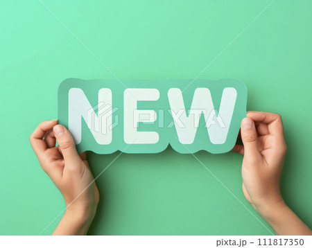 Hands holding new word on turquoise background, top view. Phrase NEW on sticker on green background. 111817350