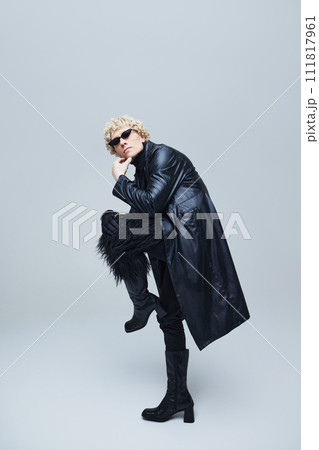 Body size portrait of confident male model in Avant-Garde attire with sunglasses, posing against grey studio background. Body size portrait of confident male model in Avant-Garde attire with sunglasses, posing against grey studio background. 111817961
