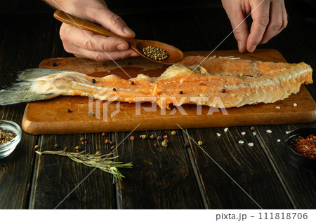 The chef prepares fresh raw fish on a wooden cutting board. Homemade delicious fish dish according to an old recipe with coriander 111818706