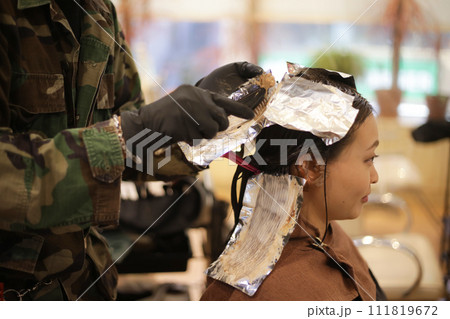 女性の髪に薬剤を塗布する男性美容師 111819672