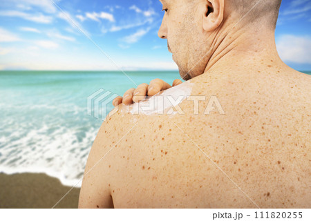 Middle aged caucasian male model applying sunscreen 111820255