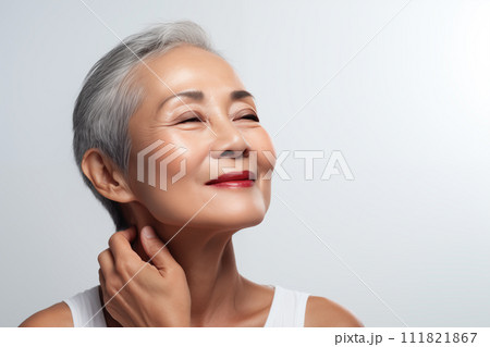 Gorgeous senior older Asian woman with makeup touching her neck and looking at camera 111821867