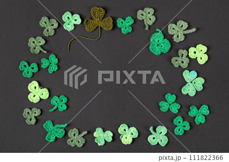 St Patrick's Day concept. Composition made of knitted green shamrocks on a black background. Holiday sign and knitted clover leaf. Copy space, flat lay, place for text St Patrick's Day concept. Composition made of knitted green shamrocks on a black background. Holiday sign and knitted clover leaf. Copy space, flat lay, place for text 111822366