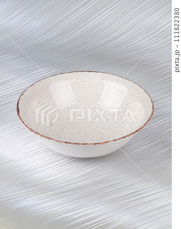 White empty deep clay plate with a spoon on a gray background. 111822380