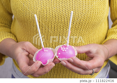 Hands hold two pink sweet candies on a stick. 111822416
