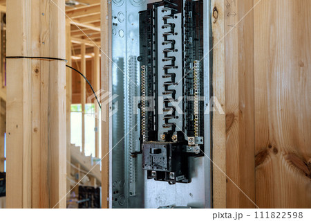 An electrical power control panel switch box mounted for circuit breaker at wooden frame beams on wall 111822598