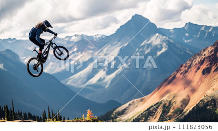 a mountain biker soaring through the air against a breathtaking mountainous backdrop 111823056