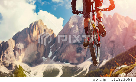 a mountain biker soaring through the air against a breathtaking mountainous backdrop 111823062
