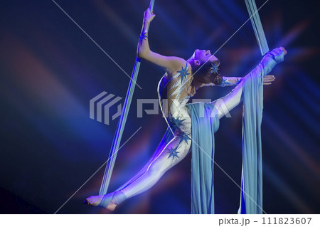 Performance by a circus acrobat artist. Girls perform aerial acrobatic elements on fabric. 111823607