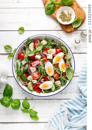 Egg and arugula fresh vegetable salad with feta cheese, top view 111825089