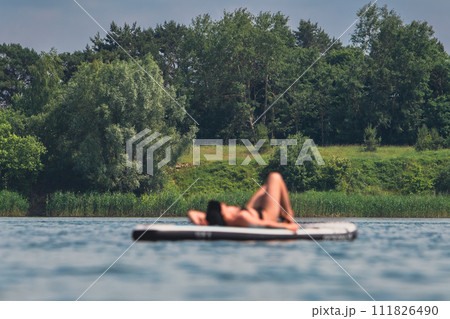woman in swimming suit sunbathing on supboard woman in swimming suit sunbathing on supboard 111826490