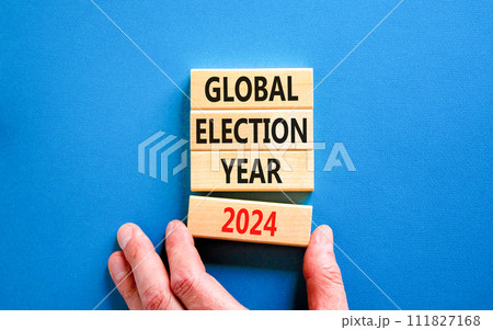 Global election year 2024 symbol. Concept words Global election year 2024 on beautiful block. Beautiful blue table background. Voter hand. Business Global election year 2024 concept. Copy space 111827168