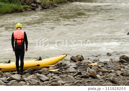 Man are preparing for rafting. The athlete is waiting for the team on the bank of the river. Man are preparing for rafting. The athlete is waiting for the team on the bank of the river. 111828203