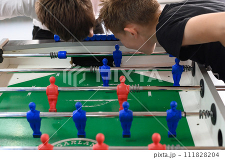Active recreation in the game room, children play table football. Active recreation in the game room, children play table football. 111828204