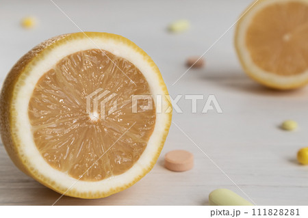 The concept of vitamin C in a minimalist style. Natural vitamin C in lemon versus synthetic vitamin C in tablets. Alternative medicine. A food additive. The concept of vitamin C in a minimalist style. Natural vitamin C in lemon versus synthetic vitamin C in tablets. Alternative medicine. A food additive. 111828281