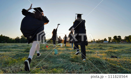 Cheerful graduates students run after school at sunset. 111828564