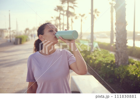 Wellness and health. Young female athlete, sportswoman with bottle of fresh clear water after sports workout outdoors 111830881