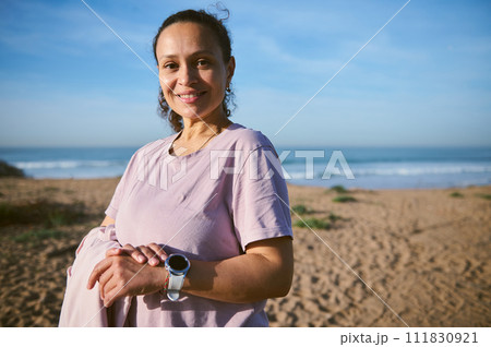 Smiling athletic woman checking pulse on mobile app while working out outdoor. People. Sport. Active healthy lifestyle. 111830921