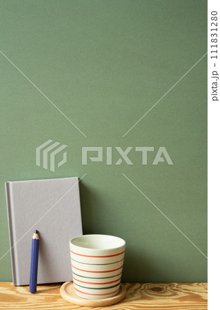 Purple diary notebook, pencil, cup on wooden desk. green wall background 111831280