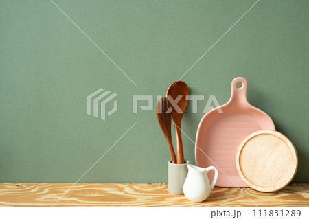 Kitchen ceramic dish plate, coaster, cutlery holder on wooden shelf. green wall background Kitchen ceramic dish plate, coaster, cutlery holder on wooden shelf. green wall background 111831289