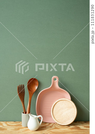 Kitchen ceramic dish plate, coaster, cutlery holder on wooden shelf. green wall background Kitchen ceramic dish plate, coaster, cutlery holder on wooden shelf. green wall background 111831290