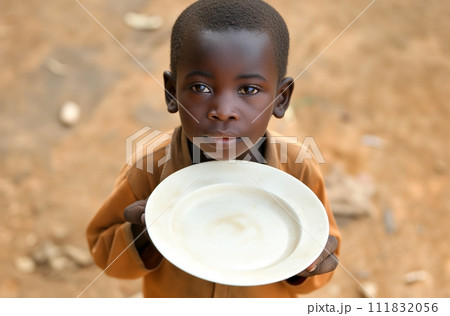 AI-generated content. A young African American boy holds an empty plate in a village setting 111832056