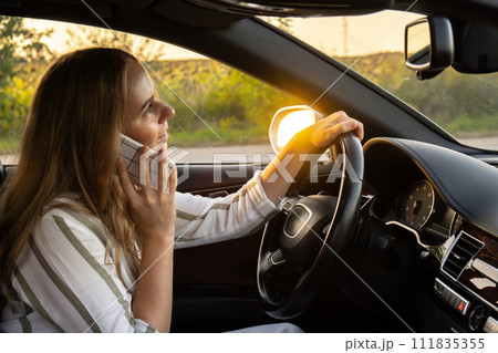 Happy young woman speaking by mobile phone while driving car. Business woman talking phone call in automobile. Unsafely risky driving multitasking Happy young woman speaking by mobile phone while driving car. Business woman talking phone call in automobile. Unsafely risky driving multitasking 111835355