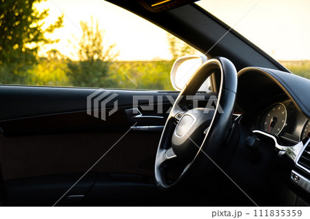 Steering wheel and Interior of modern luxury car during sunset on highway road. Details of multimedia menu control system panel, dashboard inside. Prestige sport automobile 111835359