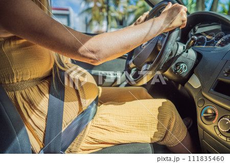 Pregnant woman driving with safety belt on in the car. Confident and capable, a pregnant woman takes the wheel, driving with care and determination as she navigates the journey of motherhood Pregnant woman driving with safety belt on in the car. Confident and capable, a pregnant woman takes the wheel, driving with care and determination as she navigates the journey of motherhood 111835460