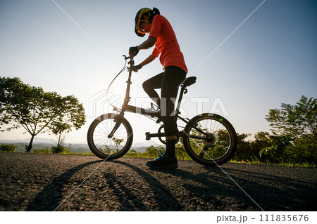 Riding folding bike on sunny mountain top road 111835676